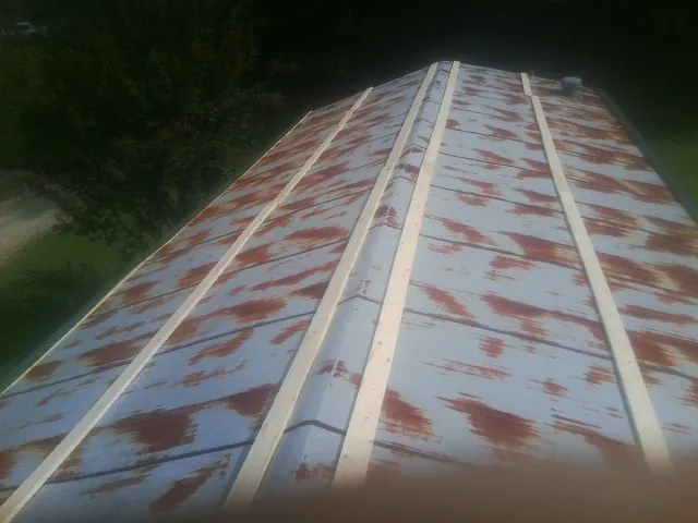 Rusted metal roof panels with new wood purlins before replacement — Storm Damage Roof Repair in Sibley by Roofing Brothers