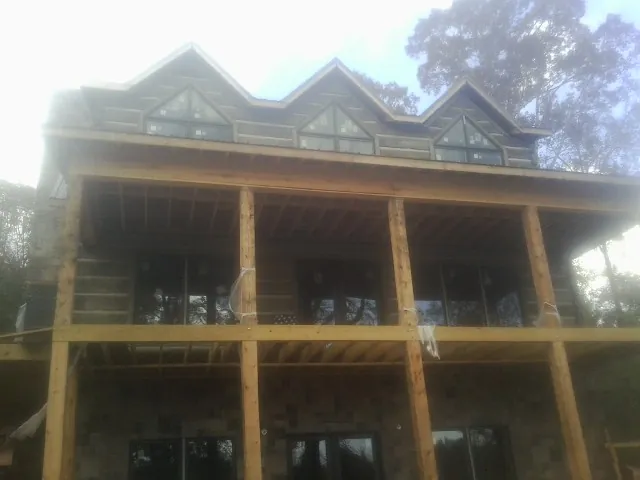 Dormers and porch framing on a large log home under construction — Roof Coating work by our crew in Sibley