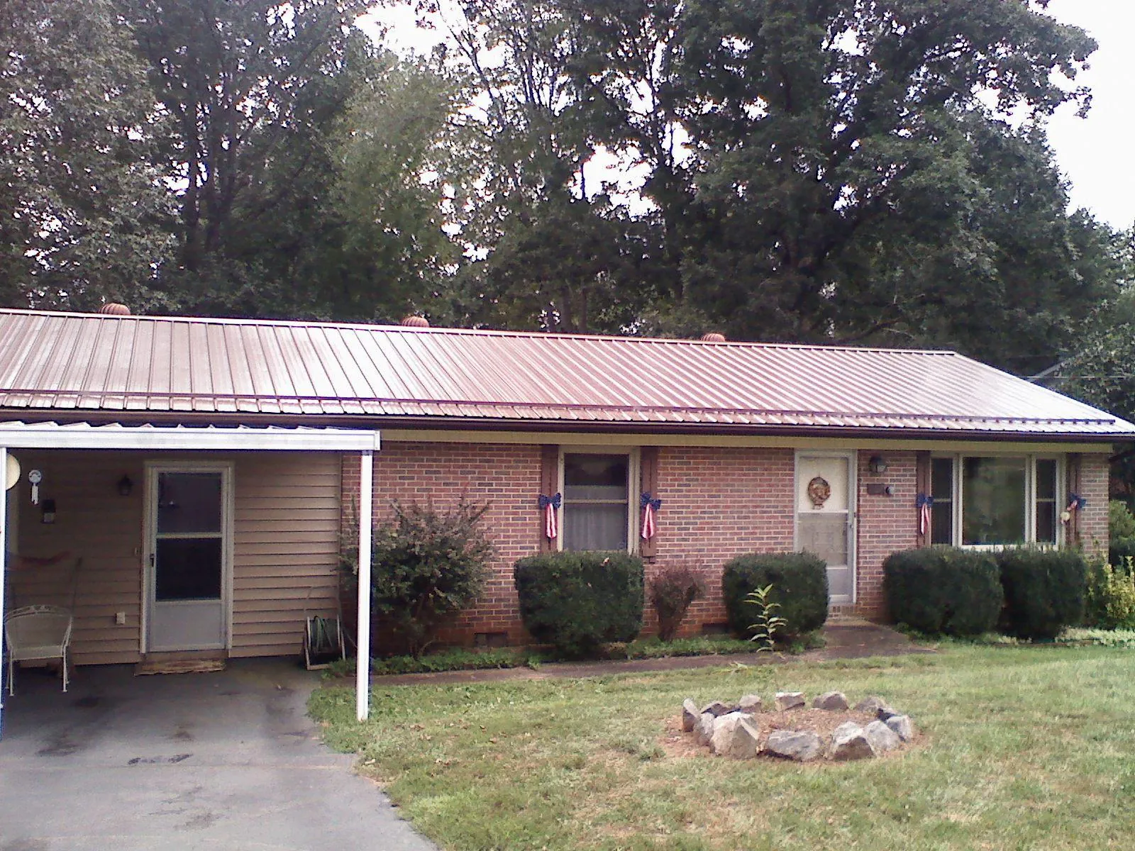 Bronze metal roof and carport on a brick ranch home — Roof Repair work by our crew in Sibley